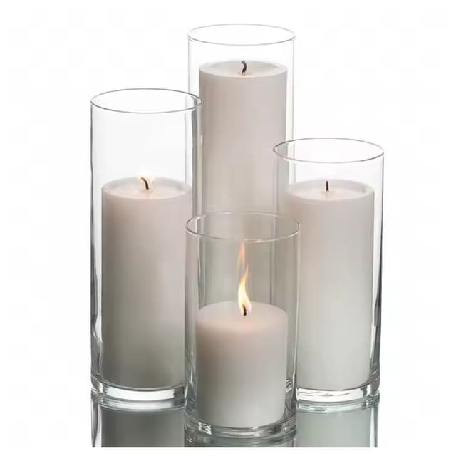 A collection of assorted glass candle holders in various heights, each showcasing white candles, creating a warm and inviting display.